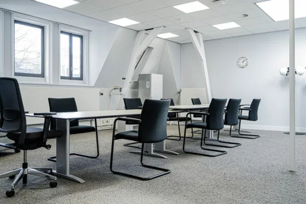 Vergaderruimte aan de Burgemeester van Karnebeeklaan met moderne inrichting, zwarte stoelen en een lang vergadertafel.